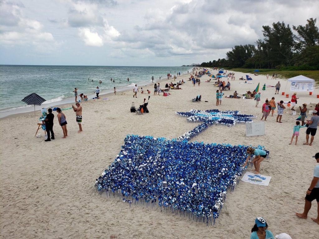Aerial of Beach scene with blue pinwheels for Children's Advocacy Center of Collier County