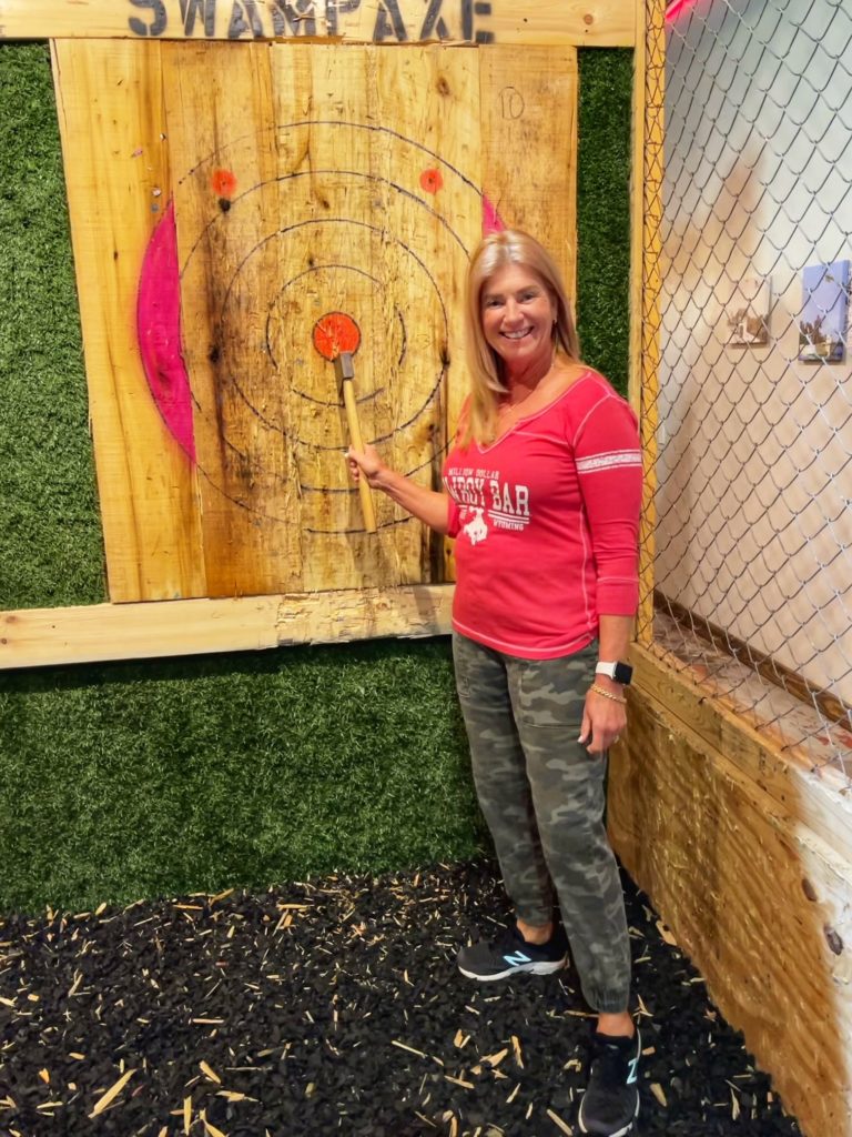 Woman standing next to her axe at axe throwing event