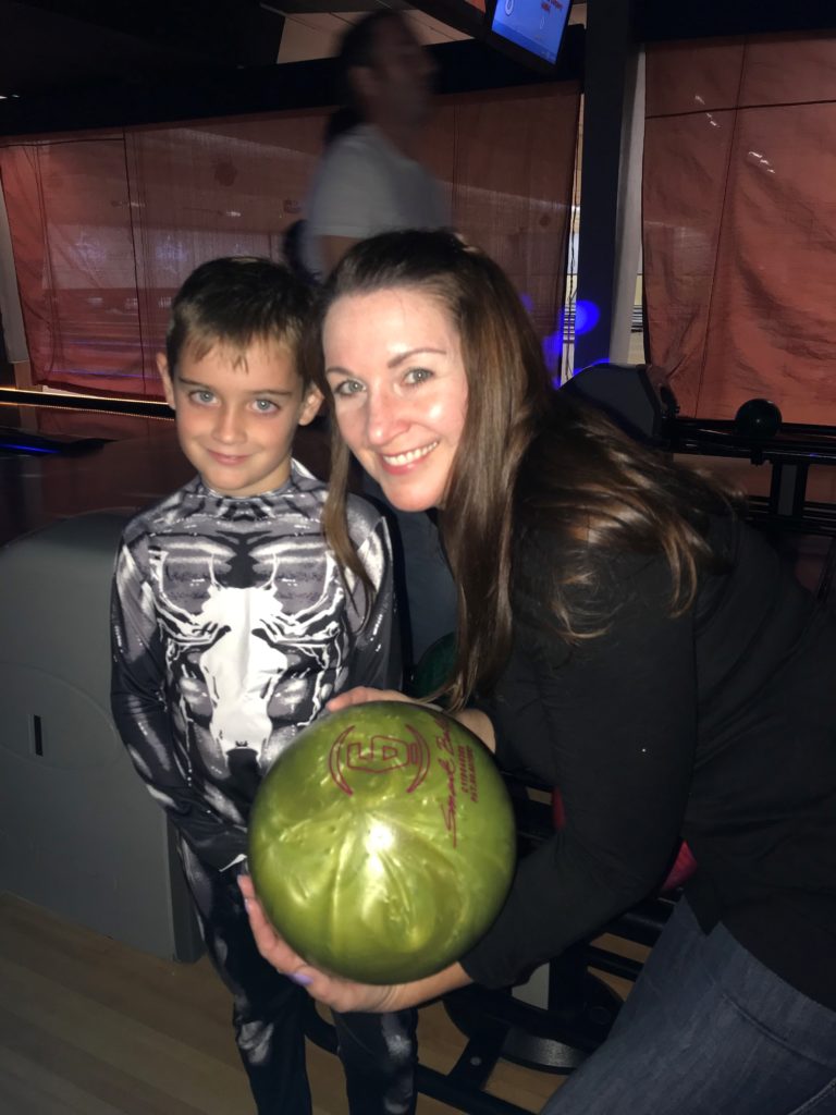 Woman standing with son holding a bowling ball