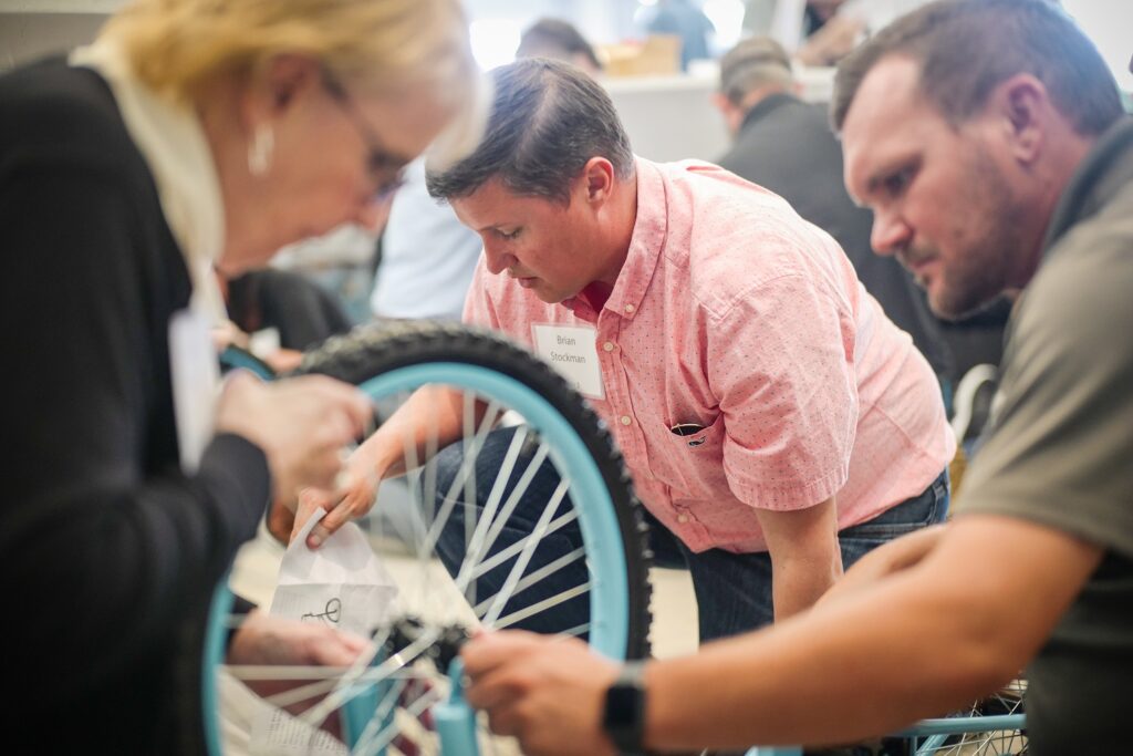 Three people building a bike at Barron Collier Company Retreat